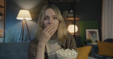 Korkunç bir gerilim filmi izleyen korkmuş genç bir kadının portresi patlamış mısır yiyor ve gece evde kameraya bakıyor. Kitle iletişim araçları ve duygu kavramı.