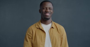 Gri arkaplandaki kameraya bakarak hava öpücüğü gönderen Afro-Amerikan bir adamın yavaş çekim portresi. İnsanlar ve sevgi kavramı.