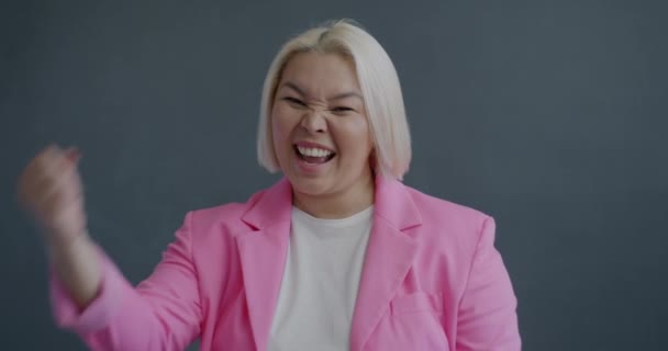 亚洲女人喜形于色 在灰色背景下欢庆成功的慢镜头 积极情绪和人的概念 — 图库视频影像