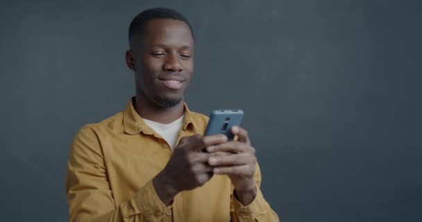 Retrato Cámara Lenta Del Hombre Afroamericano Encantado Usando Teléfono Inteligente — Vídeos de Stock