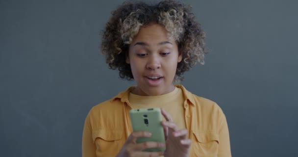 Zeitlupe Porträt Der Aufgeregten Afroamerikanerin Mit Smartphone Und Zeigt Auf — Stockvideo