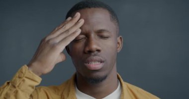 Gri arka planda baş ağrısından muzdarip Afrika kökenli Amerikalı hasta bir adamın yakın plan portresi. Halk ve sağlık sorunları kavramı.