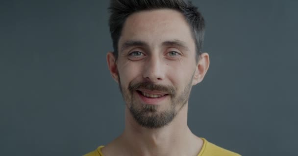 Zbliżenie Młodego Mężczyzny Wykonującego Gest Wskazujący Kamerę Uśmiechającego Się Szarym — Wideo stockowe