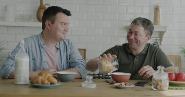 Két Boldog Meleg Férfi Reggelizik Zabpelyhet Esznek Tejjel Együtt Ülnek — Stock videók