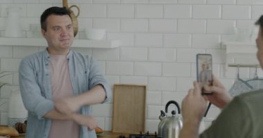 Kameraya poz veren mutlu eşcinsel erkek arkadaş evde akıllı telefonuyla fotoğraf çekerken eğleniyor. Homoseksüel ilişki ve ev hayatı kavramı.