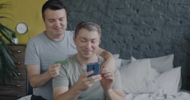 Pasangan Gay Yang Bahagia Dengan Piyama Belanja Online Dengan Smartphone — Stok Video