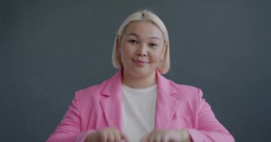 Asyalı bir kadının sevgi dolu portresi. Elleriyle kalp hareketi yapıyor. Sevgisini ifade ediyor.