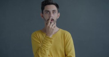 Gri arka planda parlak fikirleri olan yaratıcı genç adamın yavaş hareket eden portresi. İnsani duygu ve ifade kavramı.