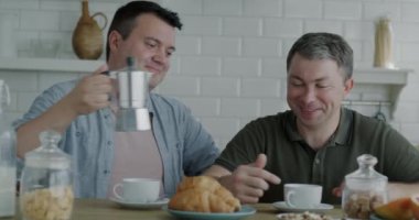 Sevgi dolu eşcinsel çift kahvaltlarını hazırlıyor ve evde sabahın tadını çıkarıyorlar. Aile hayatı ve aynı cinsiyet ilişkisi kavramı.