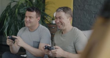 Aşırı mutlu eşcinsel çift online video oyunu oynayarak eğleniyor. Yatakta oturmuş sarılıyorlar. Oyun teknolojisi ve homoseksüel insan yaşam tarzı konsepti.