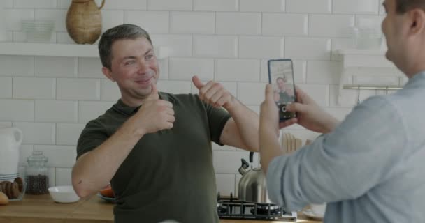 Wesoła Homoseksualistka Pozująca Smartfona Podczas Gdy Chłopak Robi Zdjęcie Kuchni — Wideo stockowe
