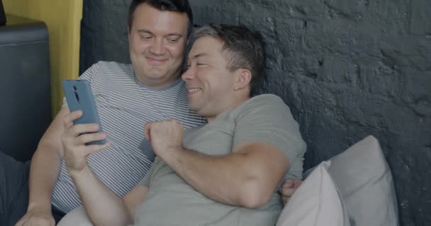 Câmera Lenta Atraente Gay Homens Amar Casal Usando Smartphone Deitado — Vídeo de Stock