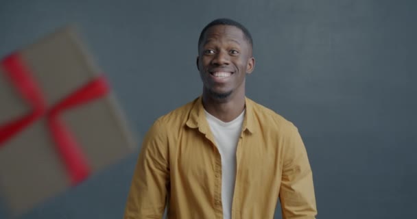 喜庆的非洲裔美国男人的慢镜头肖像在灰色背景下享受节日礼物盒 人与惊奇的概念 — 图库视频影像