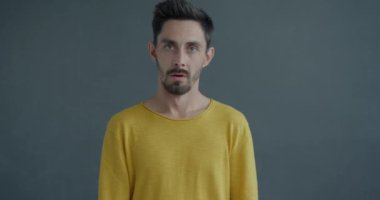 Gri arka planda utanç ve utanç hisseden bir adamın el hareketinin yavaş çekim portresi. Duygular ve insanlar kavramı.