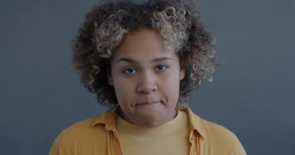 灰色の背景に目を向けているシャイなアフリカ系アメリカ人女性のクローズアップスローモーション肖像画 人と顔の表現コンセプト — ストック動画