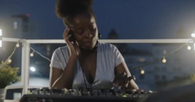 Klas Afrikalı Amerikalı kadın DJ gece partisinde müziği karıştırıyor dijital ekipman ve dansla çalışıyor.