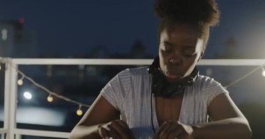 Neşeli Afrikalı Amerikalı profesyonel DJ gece partisinde çatıda ses ekipmanlarıyla müzik çalıyor. Modern yaşam tarzı ve yaratıcı meslek kavramı.