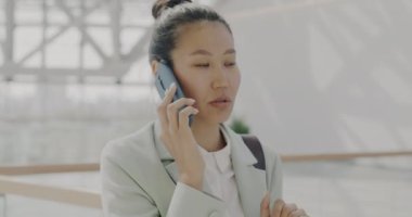Ofiste cep telefonuyla konuşan hırslı iş kadını görüşmelere odaklanmış durumda. Modern teknoloji ve iletişim konsepti.