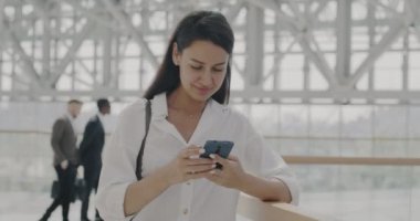Akıllı telefon kullanarak ofis lobisinde iş mesajlarını kontrol eden bağımsız girişimci. İnsanlar ve modern aygıtlar kavramı.