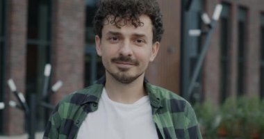 Orta Doğulu genç bir adamın yavaş çekimde çekilmiş bir portresi. Kameraya bakıp şehrin caddesinde durmaktan keyif alıyor. Duygu ve kentsel gençlik kavramı.