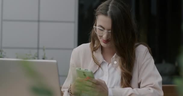Jovem Alegre Usando Smartphone Rindo Sentado Café Rua Com Laptop — Vídeo de Stock