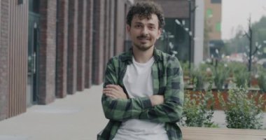 Kampüste kameraya bakarak gülümseyen çekici Orta Doğulu bir öğrencinin yavaş çekim portresi. Halk ve şehir yaşam tarzı kavramı.