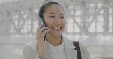 Başarılı Asyalı çalışan modern cam duvar ofis merkezinde cep telefonuyla iş konuşuyor. İletişim ve iş insanları kavramı.