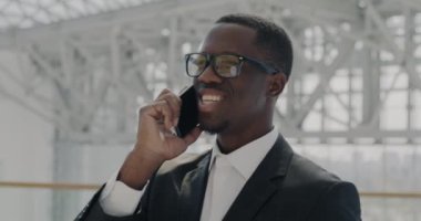 Modern havaalanında yürürken cep telefonuyla konuşan bağımsız girişimci. İletişim ve işe gidip gelen iş insanları kavramı.