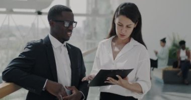 İş adamları konuşuyor ve panoramik pencereli modern ışık ofisinde çalışan belgelere bakıyor. İş geliştirme ve başarılı insanlar kavramı.