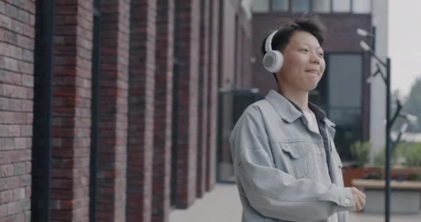 Доллі Зняв Безтурботний Азіатський Чоловік Який Танцює Слухаючи Музику Навушниками — стокове відео