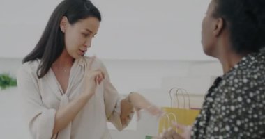 Mutlu bayan arkadaşlarıyla konuşuyor. Lobide oturmuş kese kâğıtlarını gösteriyor. Birlikte eğleniyorlar. Perakende satış ve heyecan dolu gençlik kavramı.