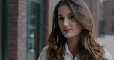 Şehrin dışında kameraya bakan ciddi genç iş kadınının yavaş çekim portresi. İş adamları ve şehir yaşam tarzı konsepti.