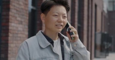 Cep telefonuyla konuşan neşeli Asyalı adam cep telefonu iletişimine odaklanmış gülümsüyor. İnsanlar ve sohbet konsepti.