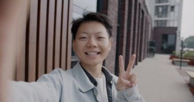 Neşeli Asyalı öğrenci portresi. Selfie çekiyor. Kameraya bakıyor ve şehirde eğleniyor. Modern teknoloji ve fotoğraf konsepti.
