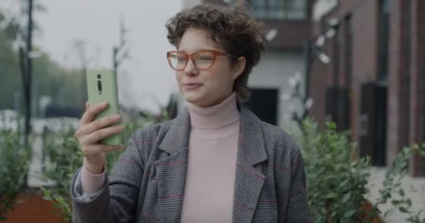 快乐的年轻女士拿着智能手机 站在城市的室外 一边打电话一边聊天 传播和千年概念 — 图库视频影像