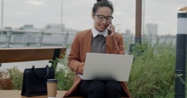 Ortadoğulu iş kadını cep telefonuyla iş görüşmesi yapıyor müşteriyle konuşuyor ve dışarıda dizüstü bilgisayar kullanıyor. İletişim ve iş konsepti.