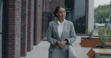 Afro-Amerikalı zarif bir iş kadınının şehir caddesinde yürürken gülümsemesi. İş adamı ve şehir yaşam tarzı konsepti.