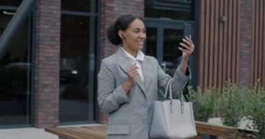 Afrikalı Afrikalı Amerikalı iş adamının yavaş çekimde sohbet etmesi. Şehir caddesinde akıllı telefonla video görüşmesinin keyfini çıkarması. İş iletişimi ve teknoloji kavramı.