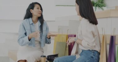 Neşeli bayan arkadaşlar alışveriş merkezinin lobisinde oturmuş alışveriş torbalarında yeni mallardan bahsediyorlar. Birlikte eğleniyorlar. Boş zaman aktivitesi ve sohbet konsepti.