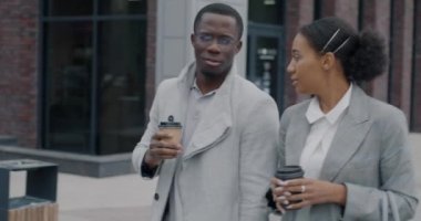 Afro-Amerikalı iş adamları ve kadın meslektaşları sokaklarda yürüyor, kahve içiyor ve sohbet ediyorlar. Modern yaşam tarzı ve profesyonel iletişim konsepti.