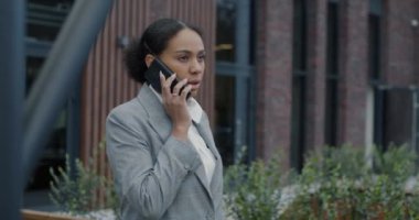 Cep telefonuyla konuşan Afro-Amerikalı iş kadını şehir sokaklarında iş projesini tartışıyor. Modern iletişim ve insan kavramı.