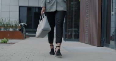 Düşük açılı kadın bacakları, modaya uygun pantolonlar ve yüksek topuklu ayakkabılar giyerek şehir caddesinde yürürken iş kadını ofis merkezine giderken..