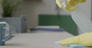 Erkek eli lastik eldivenler içinde masa temizleme masası yüzeyinde sıvı dezenfekte ederek evdeki mobilyaları dezenfekte ediyor. Temiz ev ve ev işleri kavramı.