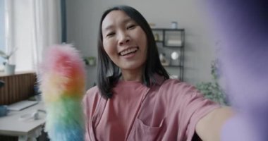 Dairesinde kameraya bakarken fırçayla selfie çeken mutlu Asyalı kadının yavaş çekim portresi. Fotoğraf ve ev işi konsepti.