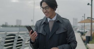 Mutlu Asyalı girişimci, açık havada başarıyı kutladığını belirten akıllı telefon dansıyla iyi haberler alıyor. İş adamı ve profesyonel başarı kavramı.