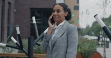 Afrika kökenli Amerikalı iş kadınının cep telefonuyla konuşması şehirde profesyonel sohbetlere odaklandı. Cep telefonu ve iş insanları kavramı.
