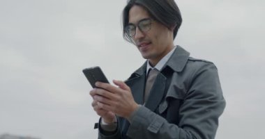 Asyalı mutlu girişimcinin eğik portresi bisikletli akıllı telefon kuryesiyle sohbet ediyor. Modern teknoloji ve çevrimiçi iletişim kavramı.