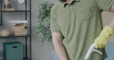 Oturma odasının yerlerini temizleyen lastik eldivenli bir adamın modern paspas kullanarak ev işlerine odaklanmış portresi. Halk ve ev kavramı.