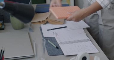 Afrika kökenli Amerikalı bir kadının ev işi yaparken çekilmiş portresi. Masada temizlik üzerine yoğunlaşmış kırtasiye malzemesi topluyor. Ev işleri ve insan konsepti.