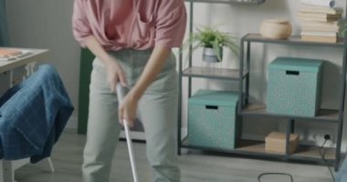 Genç Asyalı kadın elektrikli süpürgeyle halı temizliyor. Modern aletleri kullanarak evde ev işi yapıyor. Ev işleri ve insan konsepti.